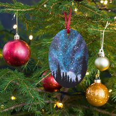 christmas ornaments hanging from the branches of a tree with lights on them and stars in the sky