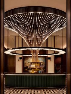 a large chandelier hanging from the ceiling above a bar in a lobby with black and white checkered flooring