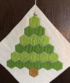 a green christmas tree ornament hanging from a wooden door with white fabric on it