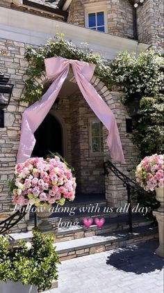 two large vases filled with pink flowers next to a stone building