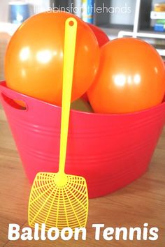 an orange and yellow ball in a red bucket with a rake on it that says balloon tennis