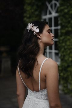 a woman wearing a white dress and flower in her hair, looking off into the distance