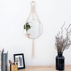 there is a mirror and some books on the shelf next to it with a plant