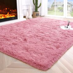 a living room with a pink rug and fireplace