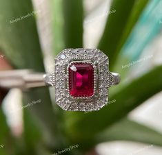 a red and white diamond ring sitting on top of a plant