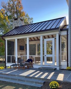 a person sitting on a chair in front of a porch with glass doors and windows