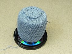 a spool of yarn is sitting on top of a cd disc with a needle