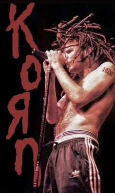 a man with dreadlocks holding a microphone in his right hand and standing on stage