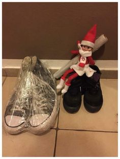 an elf sitting on top of a pair of shoes next to a plastic shoe bag