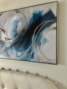 an abstract painting hangs on the wall above a white bench and headboard in a living room