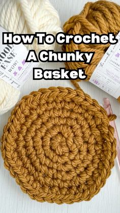 the crochet basket is next to two balls of yarn