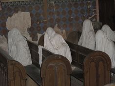 some statues are sitting in the middle of pews