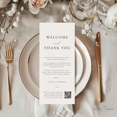 a place setting with white flowers and gold cutlery on the table for a wedding reception