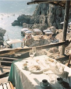 an outdoor dining area overlooking the ocean with umbrellas and tables set up for two