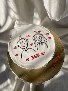 a cake with two people on it sitting on a gold plate covered in white cloth