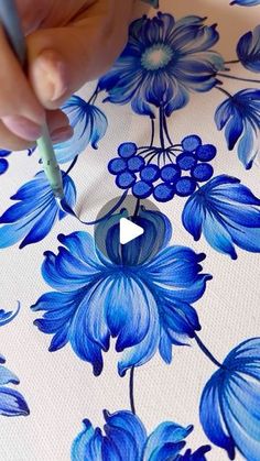 someone is drawing blue flowers on a white background