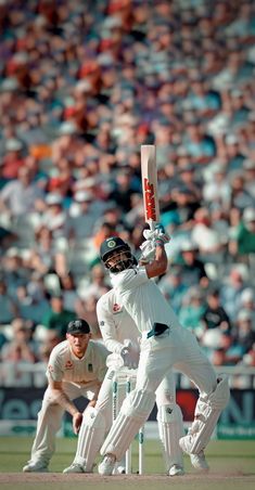 a man holding a cricket bat on top of a field in front of a crowd