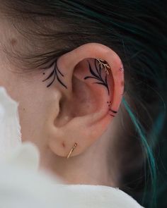 a woman's ear with small tattoos on it