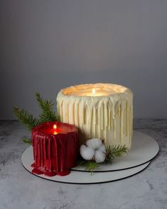 a white cake sitting on top of a plate next to a red candle