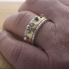 a person's hand with a gold and silver ring on it