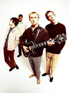 three men standing next to each other while holding an electric guitar in front of them