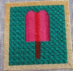 an ice cream stick is on a piece of green fabric with pink and yellow trim