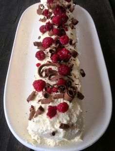 a white plate topped with cake covered in whipped cream and raspberry toppings