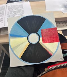 a person holding up a piece of art that looks like a wheel of fortune on a desk