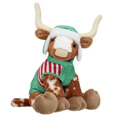 a brown and white stuffed cow wearing a green shirt with horns on it's head