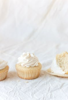 three cupcakes with white frosting sitting on top of a paper towel next to each other