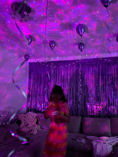 a woman standing in front of a couch under purple lights