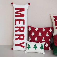 three christmas pillows sitting next to each other on top of a shelf in front of a wall