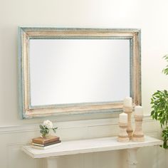 a white table topped with a mirror next to a potted plant and candle holder