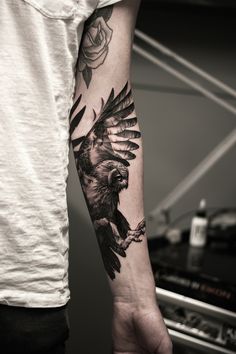 a man with a tattoo on his arm holding a bird in one hand and a rose in the other