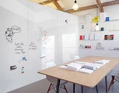 a room with a wooden table and white walls covered in writing on the wall next to two chairs