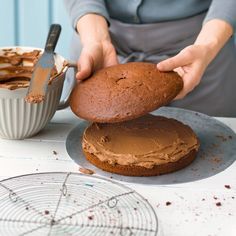 a woman is spreading frosting on a cake