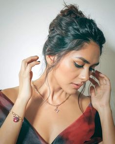 a woman in a red and black dress is holding her hand up to her ear