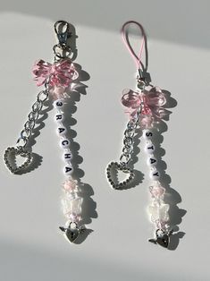 two pairs of pink and white earrings with hearts on them, hanging from a chain