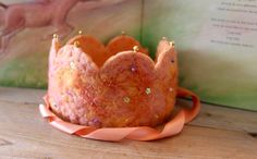 a pink crown sitting on top of a wooden table next to an open story book