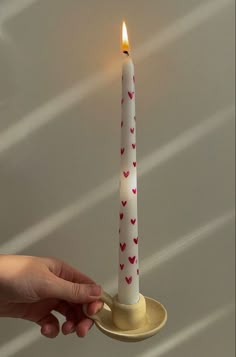 a person holding a lit candle with hearts on it