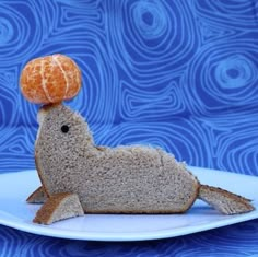 an orange sitting on top of a piece of bread in the shape of a rabbit