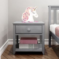 a white night stand with a pink and purple unicorn on it next to a bed