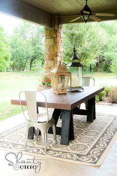 an outdoor dining area with a table, chairs and lantern on the patio floor in front of it