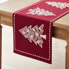 a red table runner with white embroidered designs on the edges and an arrow design at the top