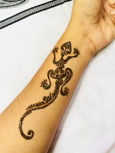 a hand with a tattoo on it that has a lizard design on the wrist and arm