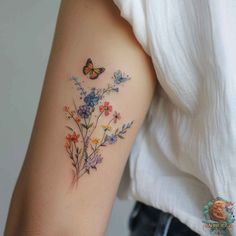 a woman's arm with colorful flowers and butterflies on the back of her shoulder