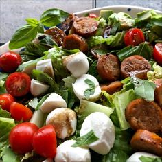 a salad with lettuce, tomatoes, mozzarella and sausage