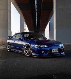 a blue sports car parked under a bridge