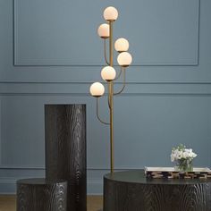 a table with four lamps on it in front of a blue wall and two vases