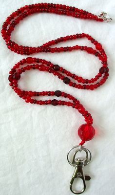 Red Beaded Lanyard This Red Beaded Lanyard can be used as a badge holder, an I.D. holder, keychain necklace, watch holder - it's a multi-use accessory for home or office! 34" in length, long enough to put on or remove overhead. It also has an easy-to-use metal lobster clasp for your convenience. It's made with red glass beads and strung on strong C-Lon beading cord. Snap-on badge holder, clip, and keyring are included to keep your badges or keys ready when you need them. This Red Beaded Lanyard Keychain Necklace, Beading Cord, Beaded Lanyard, Watch Holder, Strung Beads, Beaded Lanyards, Id Badge Holders, Red Bead, Badge Holder